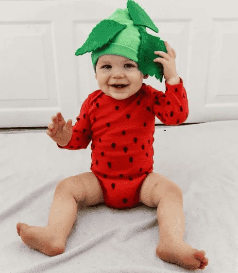 Child in strawberry onesie and hat.