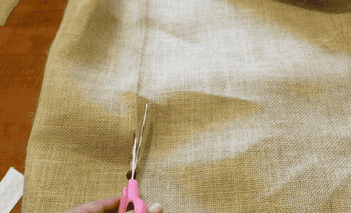 Cutting burlap with scissors.