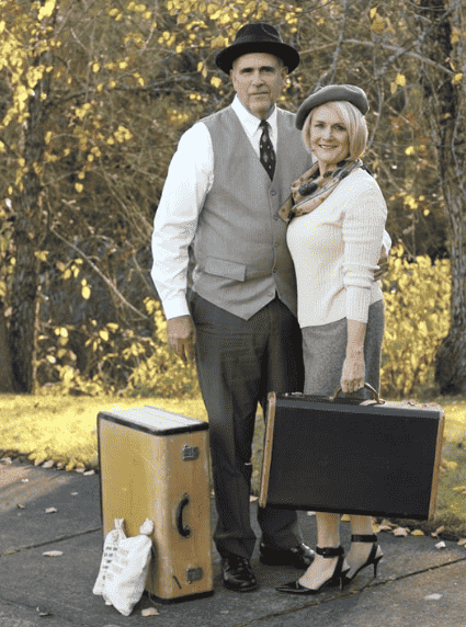 Couple dressed up as bonnie and Clyde with suitcases.
