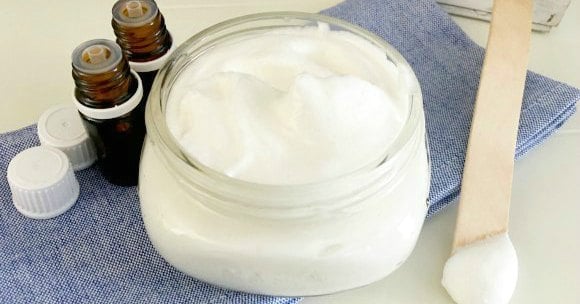 DIY Lotion in a jar beside essential oils.