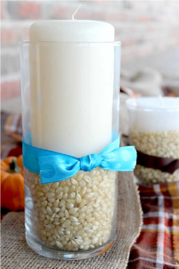 Vase with popcorn kernels and a candle.