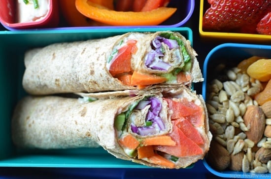 Find lots of healthy school lunch ideas here! 30 healthy back to school lunch ideas that are quick, easy and kid approved! Rainbow Wraps cut in half in a bento box with fruit and veggies.