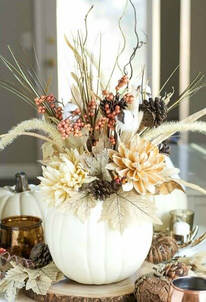 Pumpkin vase topped with flowers.