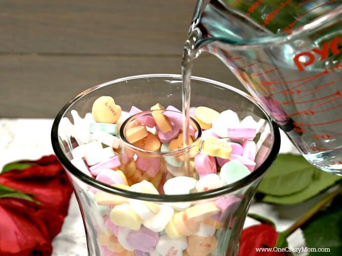Conversation hearts added to vase with water.