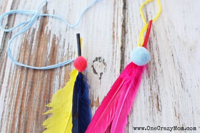 Pink, yellow, and blue feathers with pom poms added with embroidery floss attached.