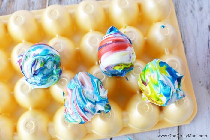 Shaving cream covered eggs on egg carton.