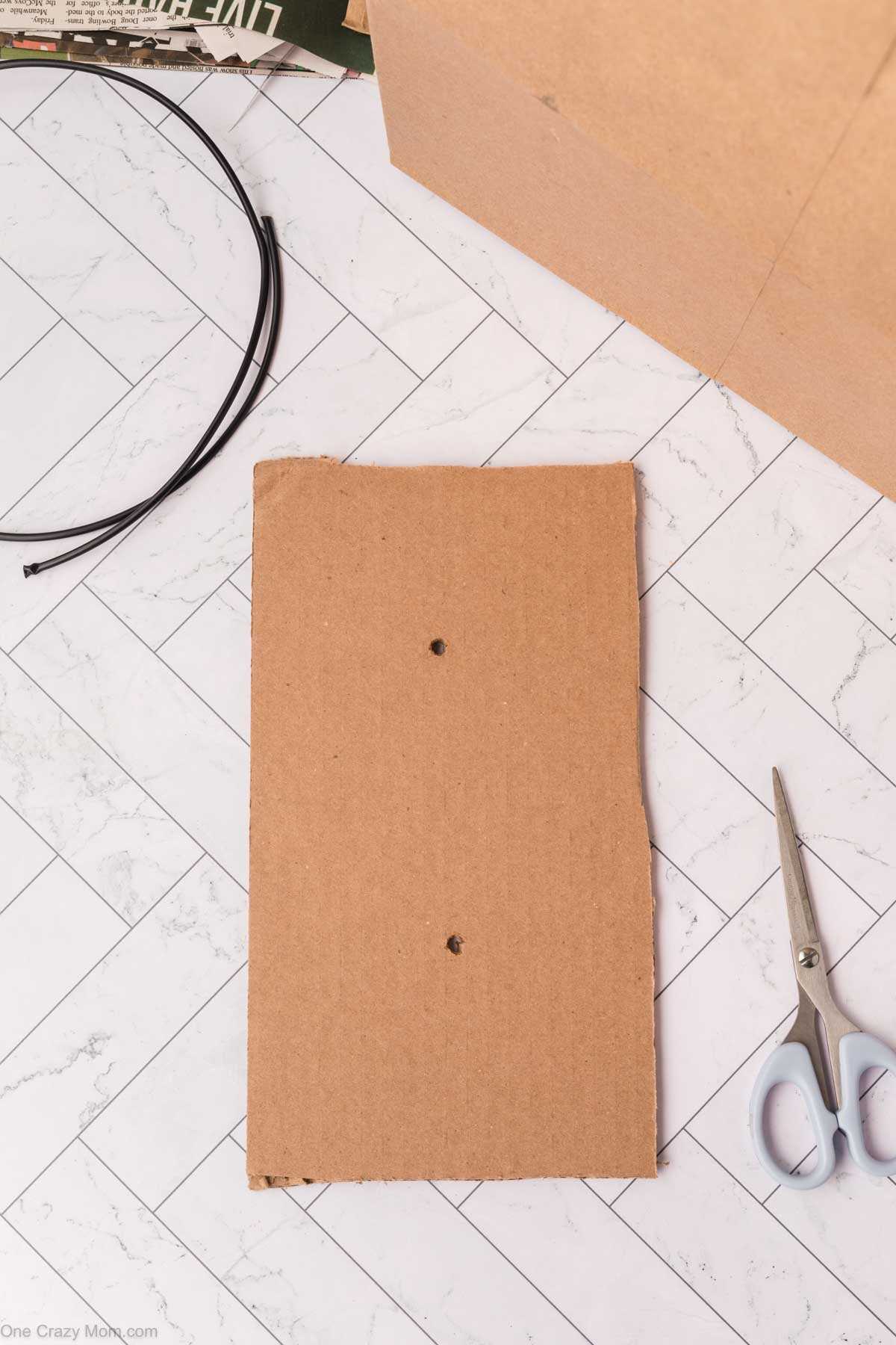 Strip of cardboard with two holes in it.