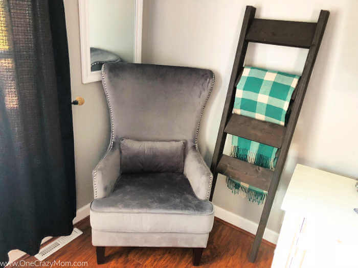 Ladder leaned against the wall with blankets beside a chair.