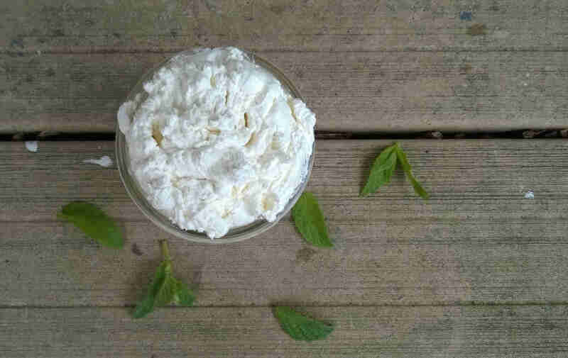 Mint body butter beside mint leaves.