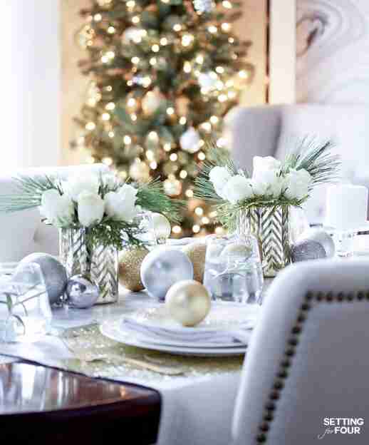 Gold and white table setting with ornaments and flowers.