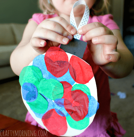 Child holding ornament made from a paper plate.