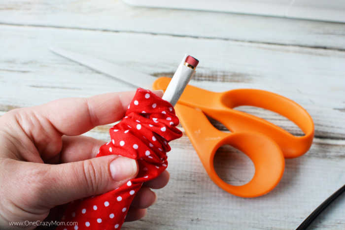 Elastic taped to the pencil and thread through the fabric.