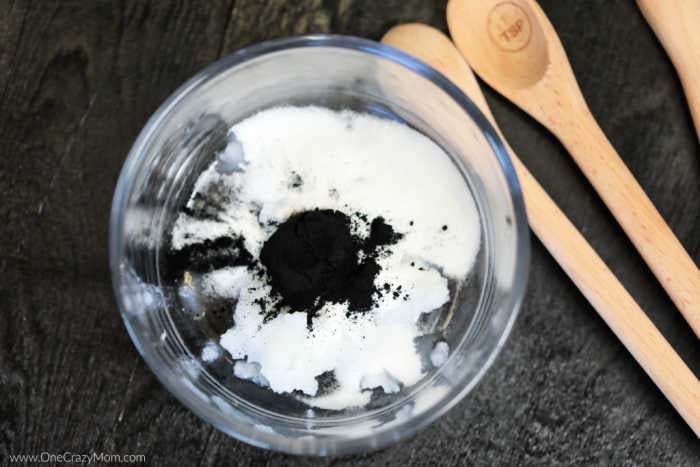 Charcoal powder and baking soda mixed into coconut oil in mixing bowl.