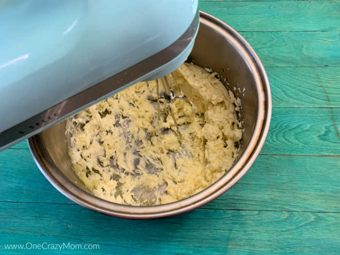 Mixture in a pan being beat with mixer.
