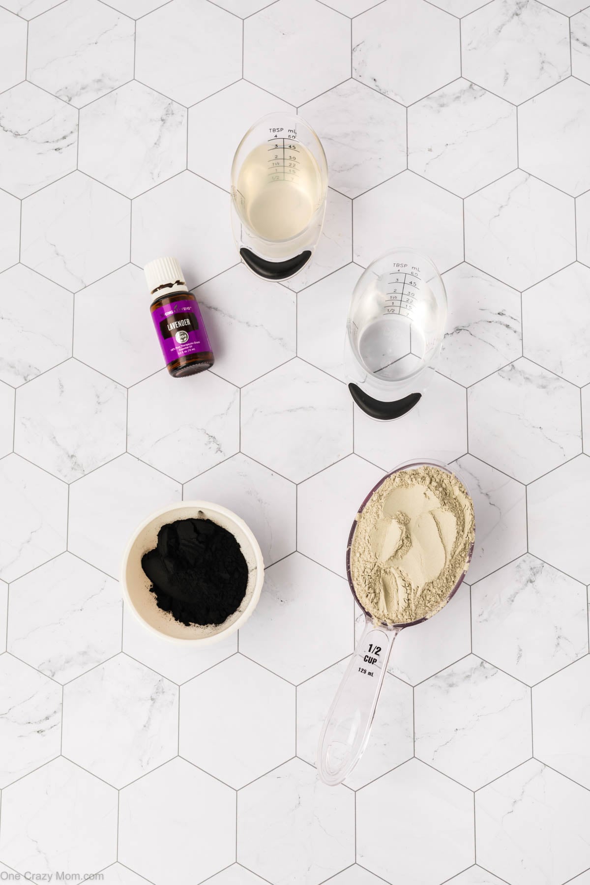 Supplies for charcoal mask - bentonite clay, activated charcoal powder, coconut oil, water, lavender essential oil.