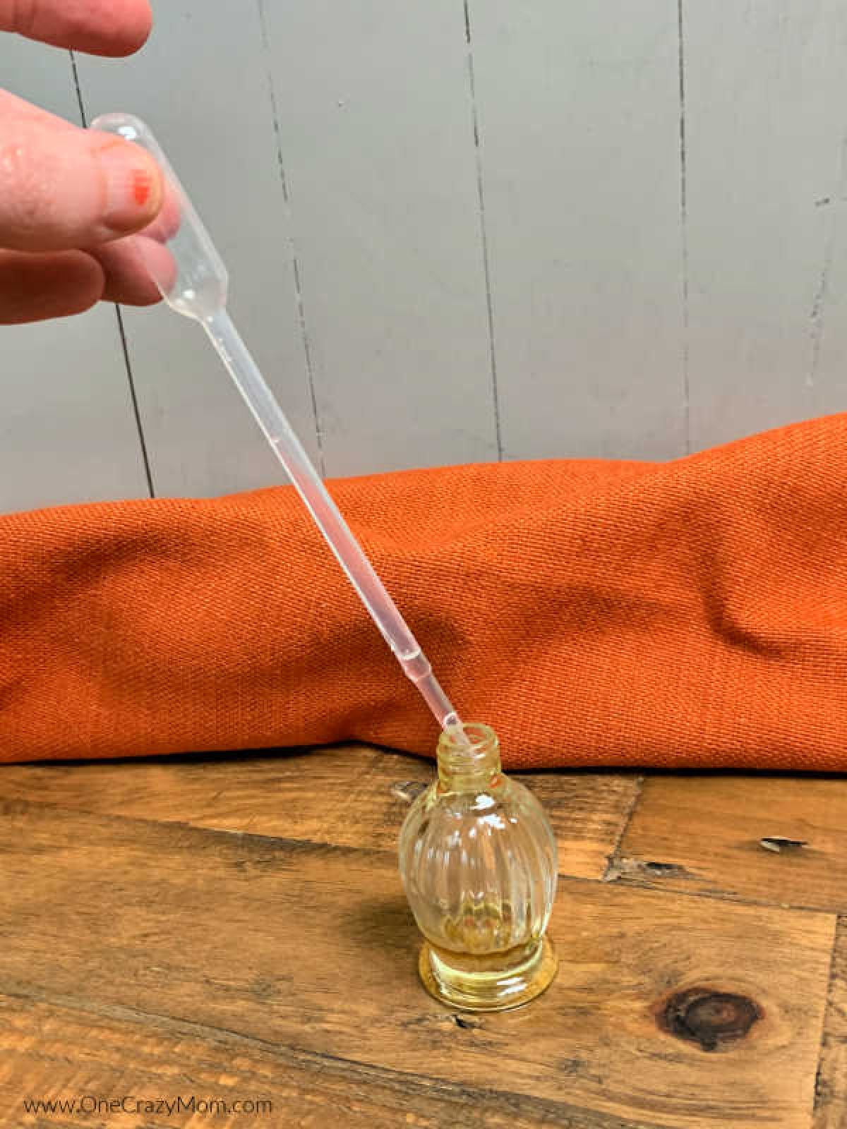 Dropper with coconut oil being added to bottle.
