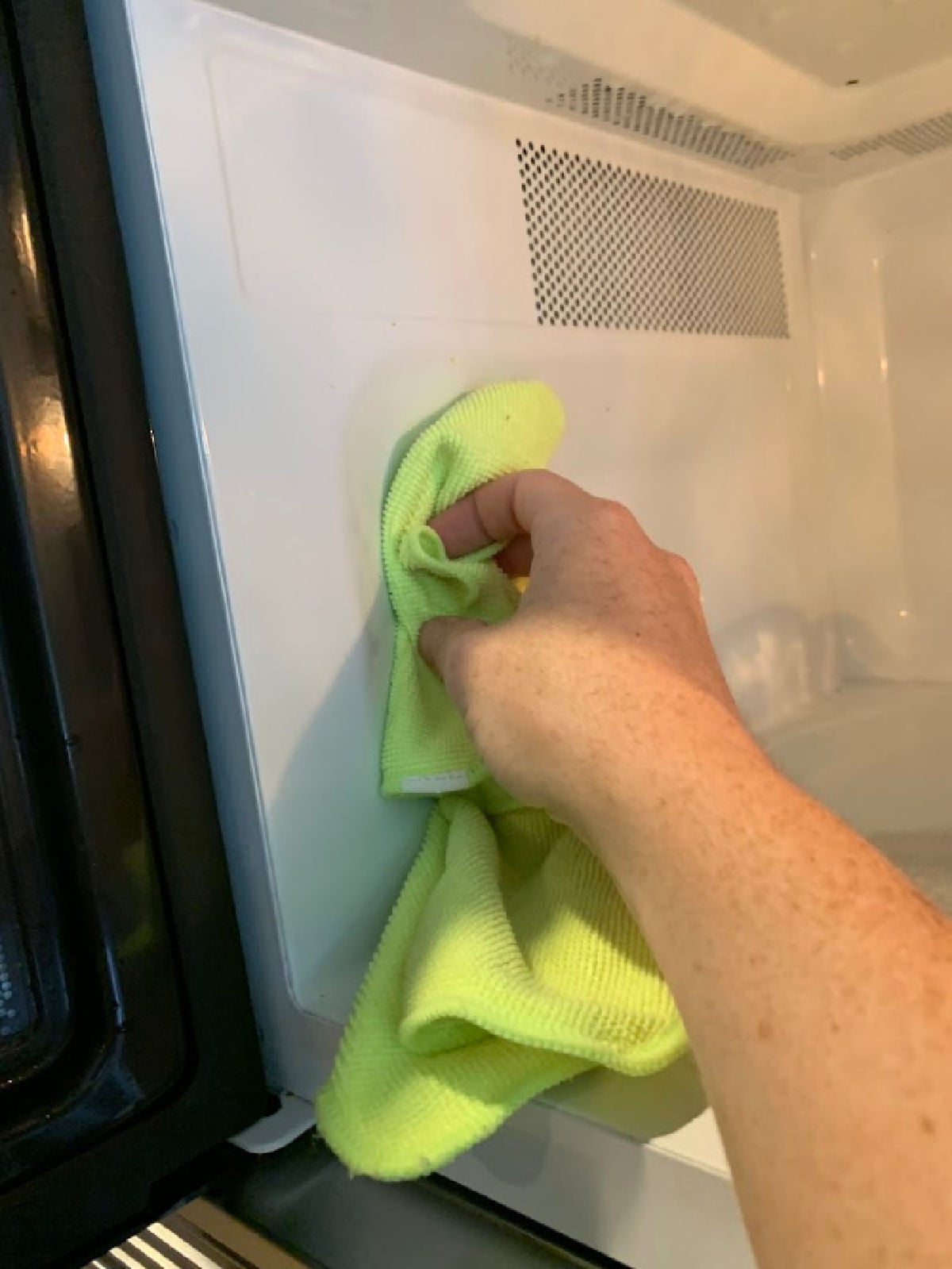 Cloth wiping down microwave.