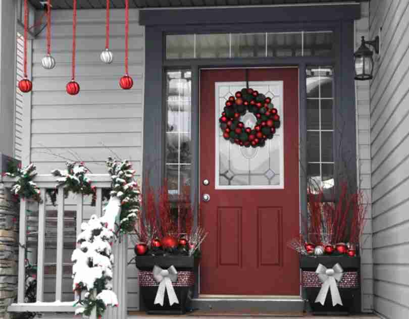 Garland and planters on porch with Christmas decor.