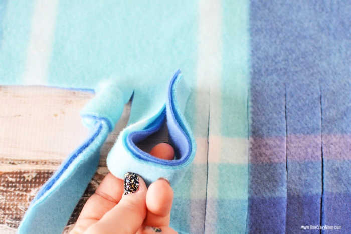 Knots being tied on each strip of the blanket.