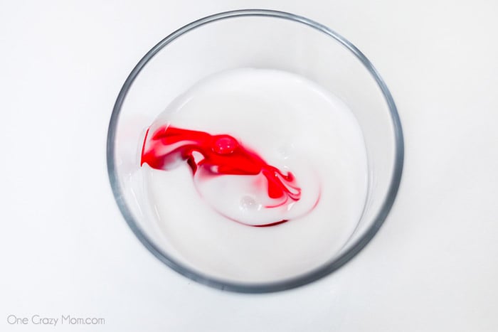 Mixing glue with red food coloring in a bowl
