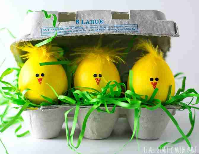 Chick eggs in egg carton with green Easter grass.