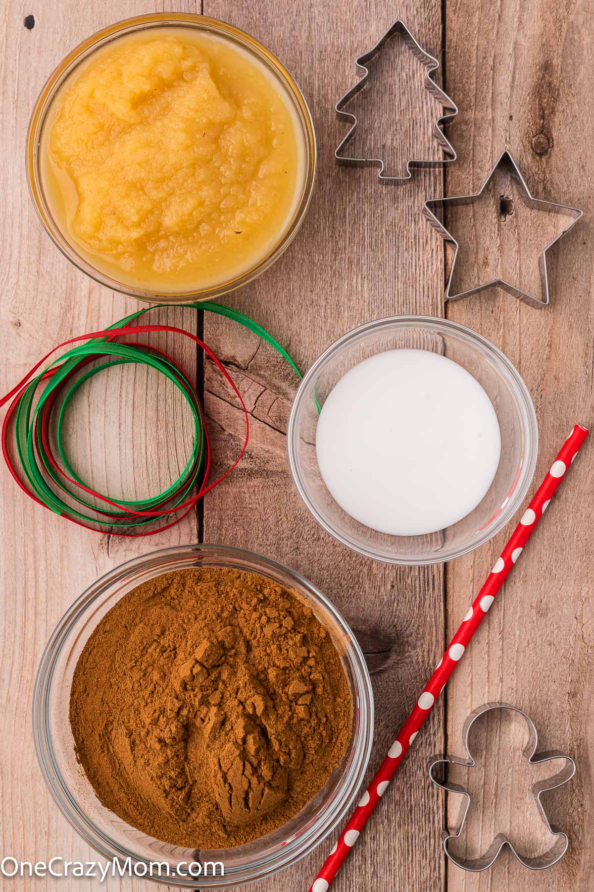 Supplies for cinnamon ornaments- applesauce, cinnamon, glue, cookie cutters, straw.