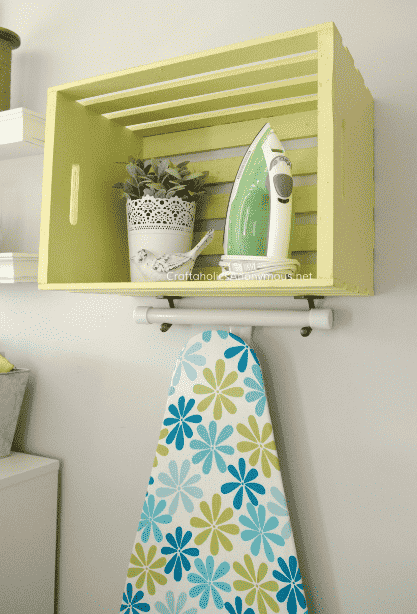 Crate on wall with ironing board hanging.