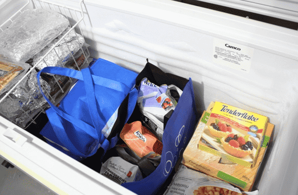 Grocery bags holding food in the freezer.