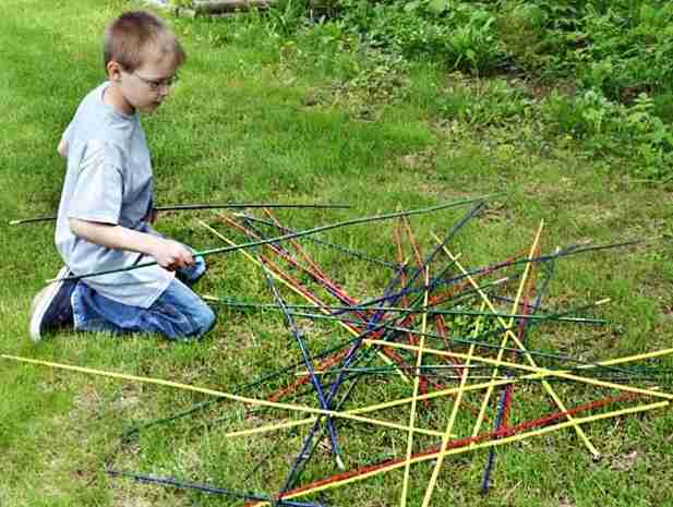 Giant pick up sticks in the yard with child.