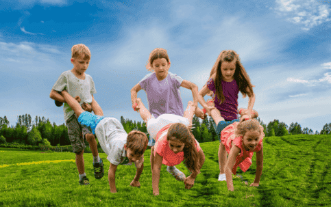 Wheelbarrow Race with kids in field.