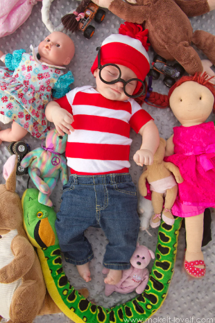 Waldo costume on child surrounded by stuffed animals.