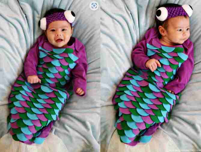 Baby fish costume on young baby laying down.