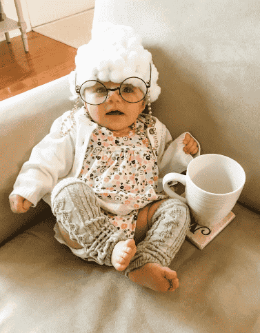 Baby dressed up as a little old lady.