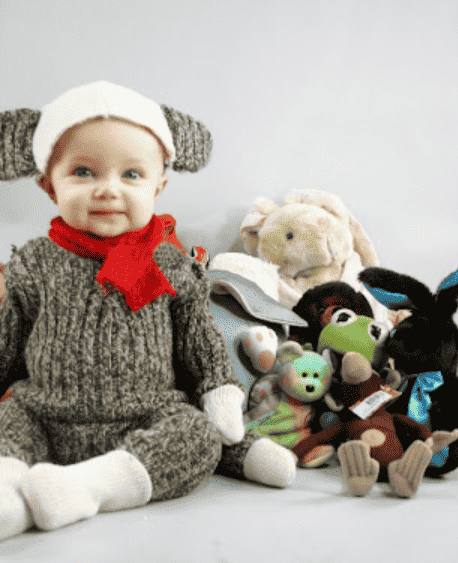 Baby dressed as sock monkey sitting up.