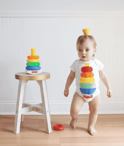 Stacking toys beside a baby dressed as stacking toy.