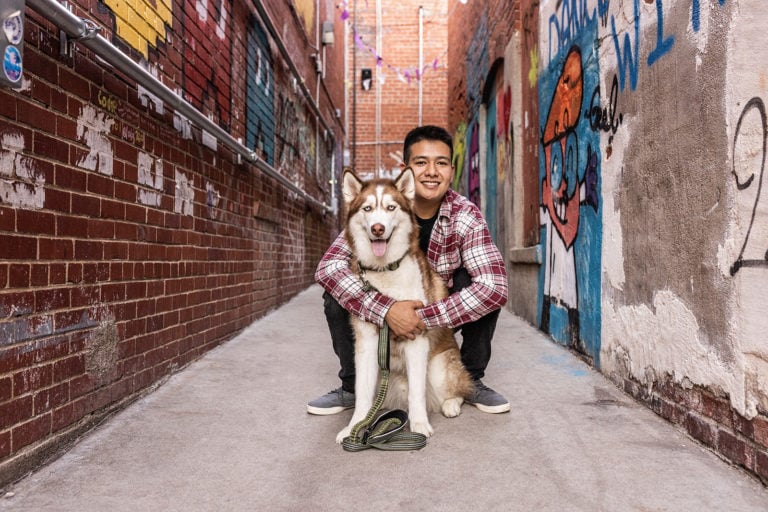 Guy standing by a dog.