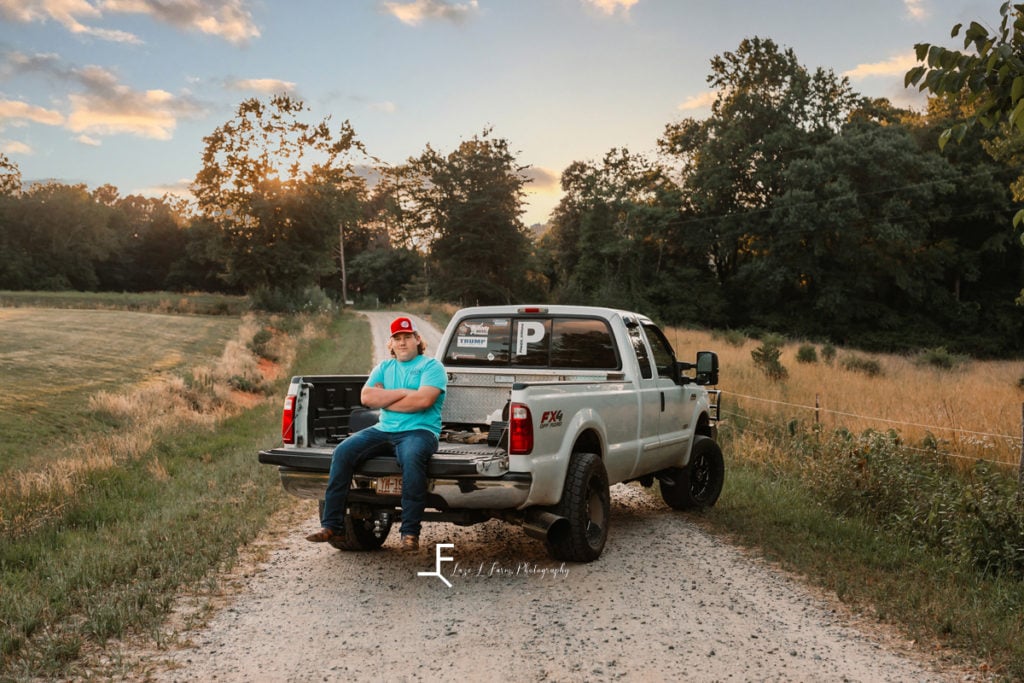 Truck with boy in back in field.
