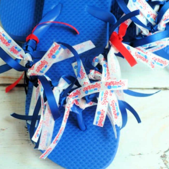 Make these Patriotic ribbon flip flops for less than $5 and in just 20 minutes! Jazz up plain flip flops and turn then into 4th of july flip flops. Patriotic flip flops with ribbon.