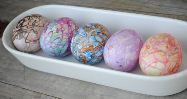 We have 25 Easter egg decorating ideas that are so easy and the kids will love. Gather the family together and make lots of sweet memories with these ideas. Eggs decorated with crayons on white tray.