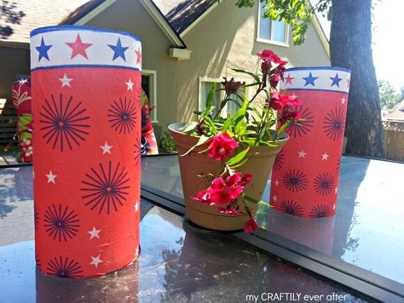 Check out these Fourth of July Crafts. You can make any celebration patriotic with these 4th of July Crafts for your home. Patriotic candle holders on outside table.