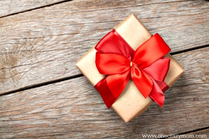 If you're looking for non toy Christmas gift ideas for kids, we have a big list of ideas. These ideas will provide lasting memories and hours of fun on non toy gifts that kids want. #onecrazymom #christmasgiftideas #nontoygifts Photo of gift with red bow.