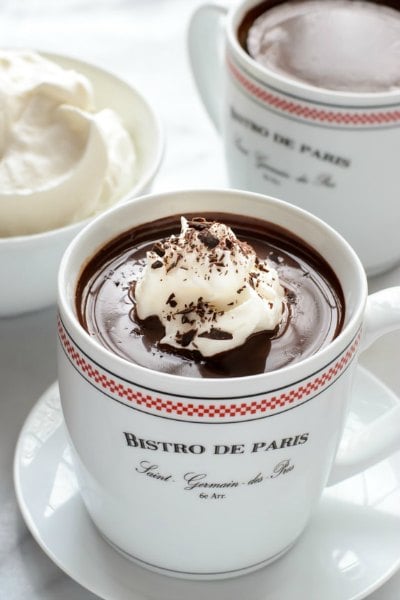 Try these easy hot chocolate recipes for an amazing treat everyone will love this Winter. 20 of the best hot cocoa recipes. You will love these homemade hot chocolate recipes that are made in the crock pot, some with cocoa powder. Learn how to make your own hot chocolate at home! #eatingonadime #hotchocolaterecipes #drinkrecipes #winterrecipes French hot chocolate in a cup sitting on a saucer.