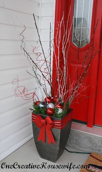 Get your home ready for Christmas with these 25 Christmas Porch Decorating Ideas. Beautiful Christmas porch ideas that are simple and budget friendly! LED branches in urn on porch.