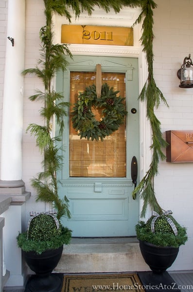 Get your home ready for Christmas with these 25 Christmas Porch Decorating Ideas. Beautiful Christmas porch ideas that are simple and budget friendly! Greenery around the front door.