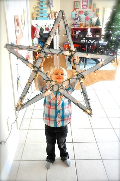 Get your home ready for Christmas with these 25 Christmas Porch Decorating Ideas. Beautiful Christmas porch ideas that are simple and budget friendly! Child holding giant star with lights.