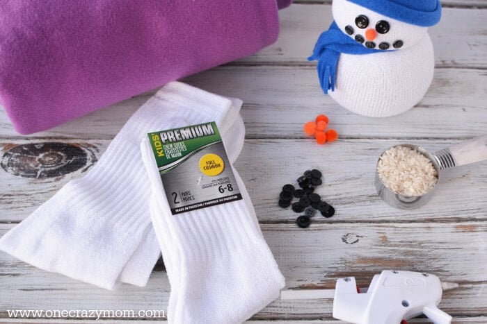 You will love learning how to make sock crafts! Find out how to make a snowman made out of socks. This DIY Sock Snowman craft is so cute and simple to make! Supplies needed for snowman craft - socks, rice, ribbon, black buttons, pom poms, paper plate, scissors, fleece, stickers.