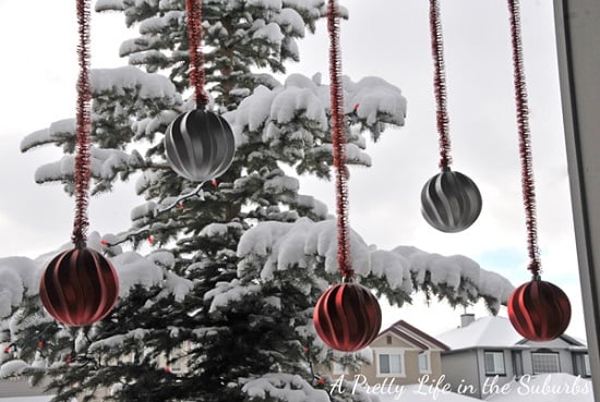 Get your home ready for Christmas with these 25 Christmas Porch Decorating Ideas. Beautiful Christmas porch ideas that are simple and budget friendly! Ornaments hanging on porch.