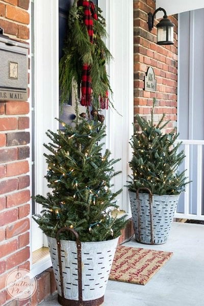 Get your home ready for Christmas with these 25 Christmas Porch Decorating Ideas. Beautiful Christmas porch ideas that are simple and budget friendly! Christmas tree planters on both sides of the front door.