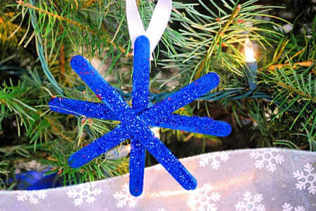 Find Easy Christmas Crafts for kids that are easy to do. They will love these Christmas crafts for kids. 20 Christmas craft ideas for kids that are frugal and great for gifts or ornaments. These fun projects are great for toddlers and older kids too. Perfect for school or for Christmas decorations! #onecrazymom #christmascrafts #kidcrafts Glitter snowflake hanging on tree.