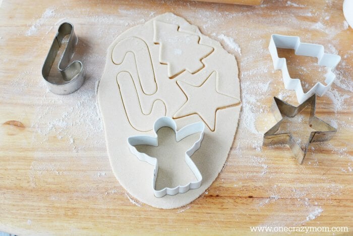 Make special memories with this simple and fun Salt Dough Ornament Recipe for Christmas. Learn how to make salt dough ornaments so easy the entire family can help! This great ornament DIY is perfect for kids. #onecrazymom #christmasornaments #DIYornaments #saltdoughornaments Cooking cutters being used to make shapes.